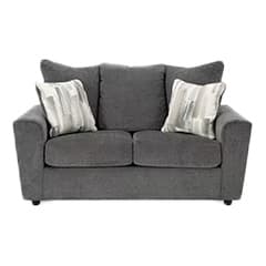 A plush gray loveseat with two seat cushions and two back cushions, adorned with two patterned throw pillows on either side.