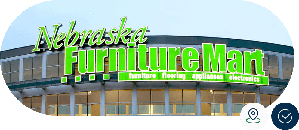 Sign on the exterior of Nebraska Furniture Mart, advertising furniture, flooring, appliances, and electronics in bright green letters.