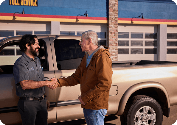 Two men speaking in front of a truck.