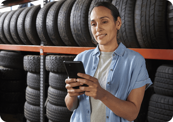 A woman looking at her phone in a tire shop.