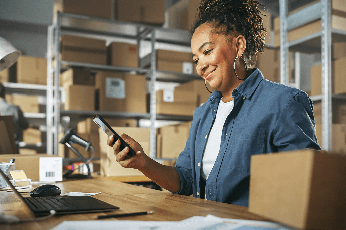 woman in a warehouse smiling at her phone